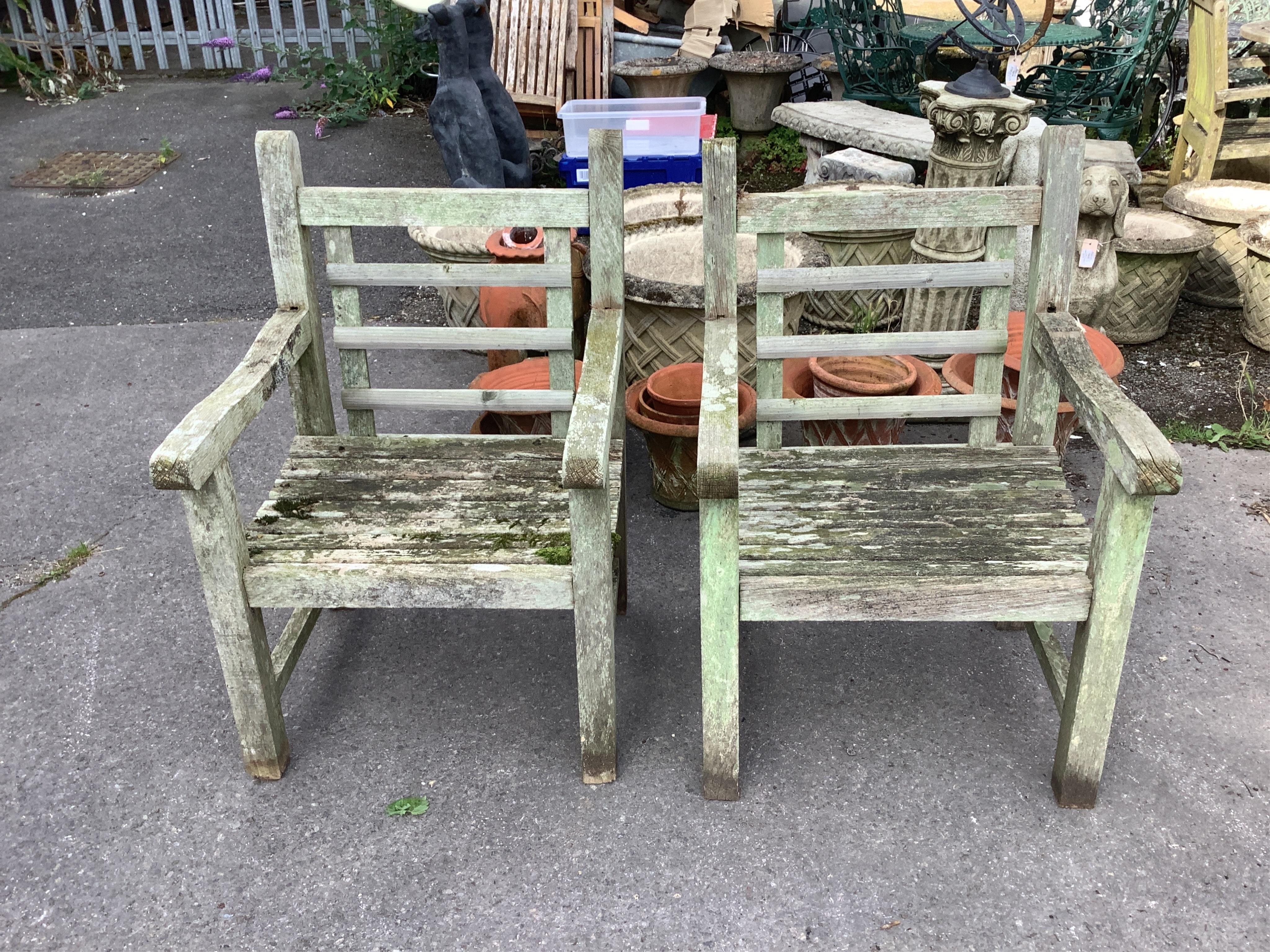 A pair of weathered teak garden armchairs, width 63cm, depth 64cm, height 94cm. Condition - fair